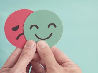 happy sad faces on colourful circles held by human hands